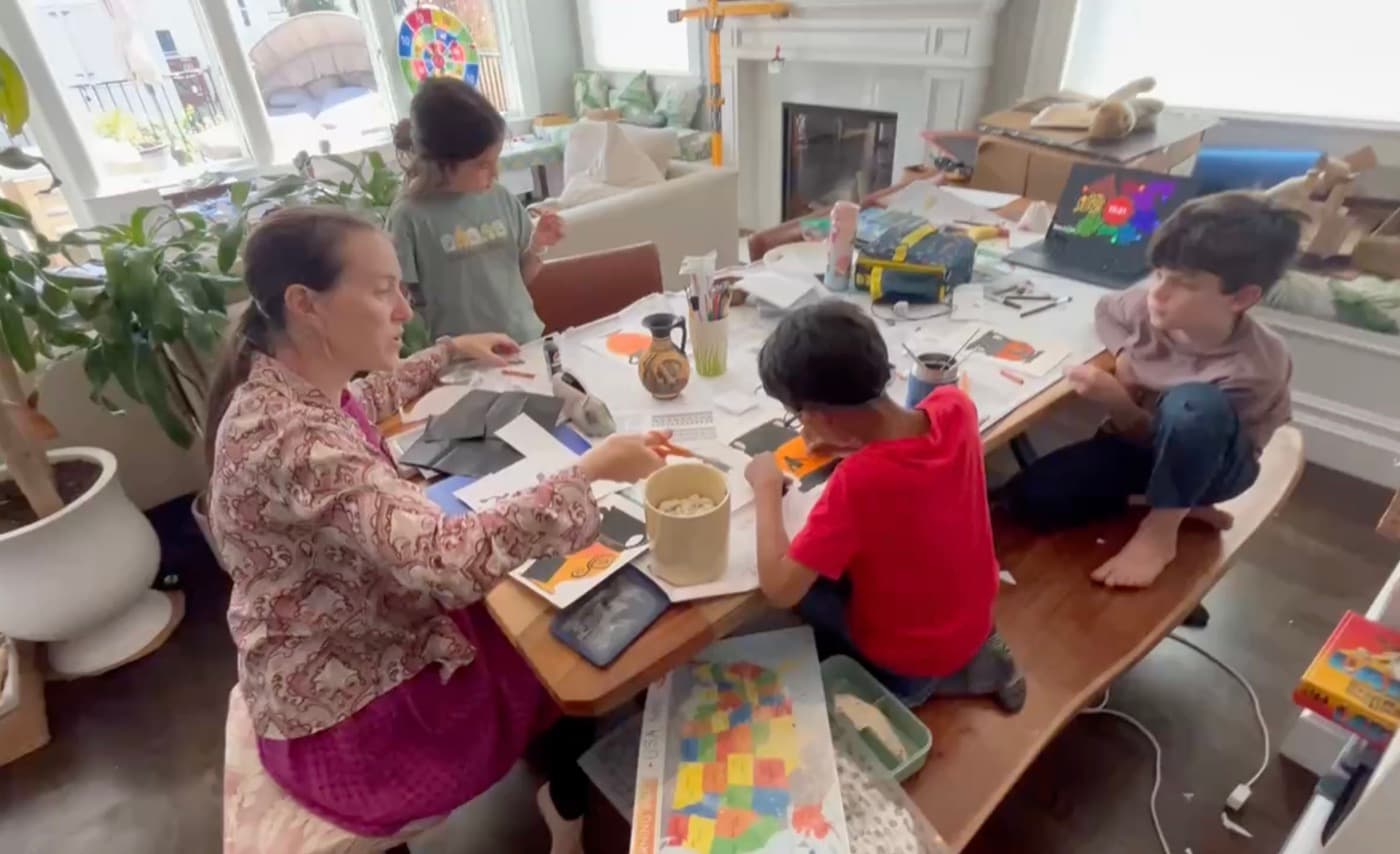 A tutor working on an art and history project with kids around a dining table